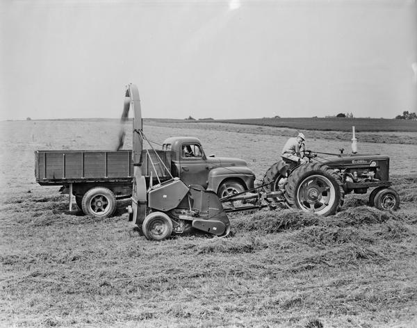 Men operating a Farmall Super M-TA tractor, a forage harvester and an International R-150 truck.
