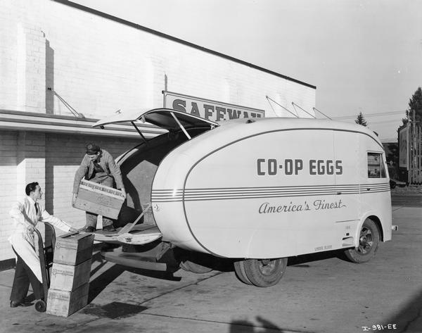 Two deliverymen unloading boxes of eggs from their International D-300 truck. The truck was owned by Co-op Eggs.
