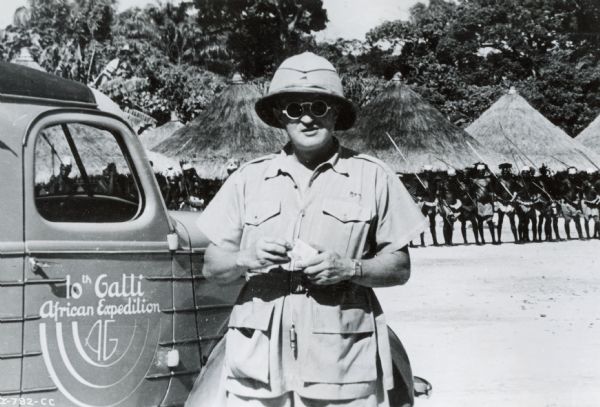 Commander Attilio Gatti poses in front of a Congolese village during his tenth expedition to Africa. The expedition was sponsored by International Harvester, and Gatti is standing next to an International truck.
