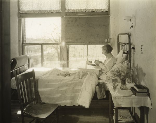 Tuberculosis Patient Making Dolls Tuberculosis patient sitting in a sanatorium bed making dolls.
