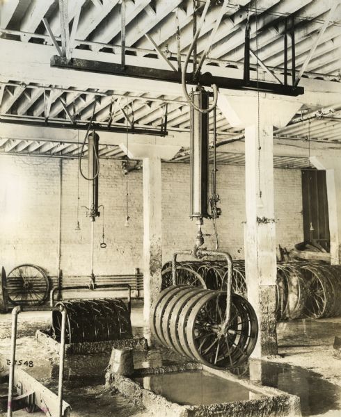 Metal wheels hanging from the ceiling at International Harvester's Plano Works. The wheels appear to ready for dipping in a liquid bath. The factory was later known as "West Pullman Works."
