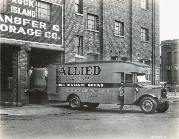 Men loading boxes from a Rock Island Transfer and Storage building onto an International truck operated by the Allied Van Lines company.