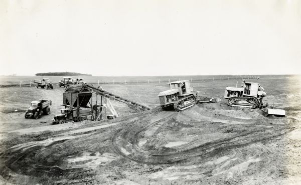 Construction equipment and dump trucks belonging to the Wagner Erling Company work on the beginnings of Highway 77 in South Dakota.
