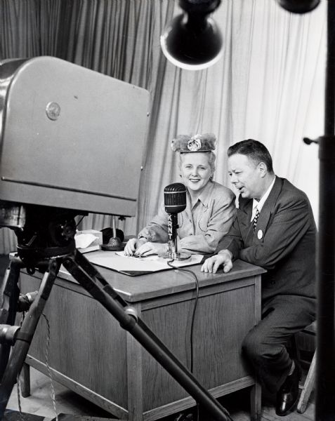 Actress Betty Wells sitting next to a man, possibly a KRNT radio personality, for a simultaneous radio and television broadcast from the Iowa State Fair.