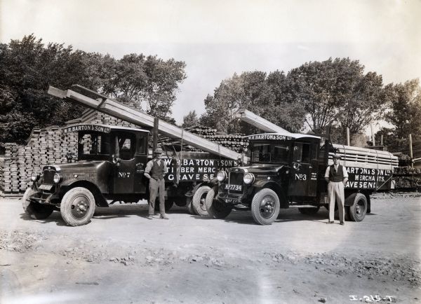 Men stand next to two International trucks loaded with lumber at W.R. Barton and Son Ltd. Timber Merchants in England.