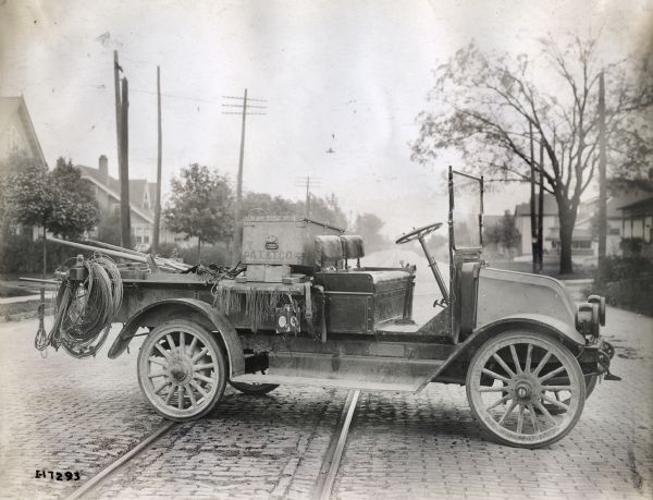 An International truck used by the AT&T Company is parked across cable car tracks on a cobblestone street. The truck may be a Model H or 21.