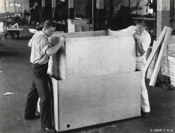 Two factory workers at the West Pullman Works place an inner steel box into a McCormick-Deering Milk Cooler.