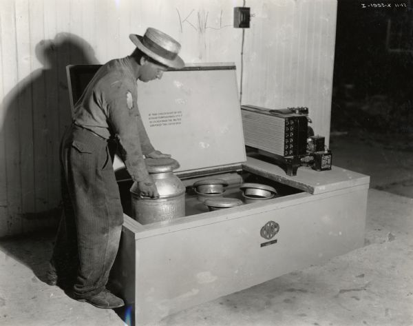 John R. Hauen? (Haven?) places a milk canister into a McCormick-Deering Milk Cooler set into the ground.