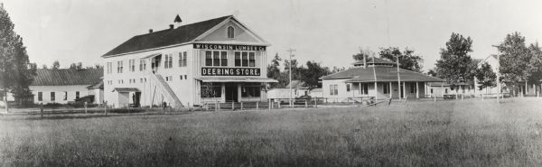 External view from a field of the Wisconsin Lumber Company's "Deering Store." A number of other buildings surround the store.