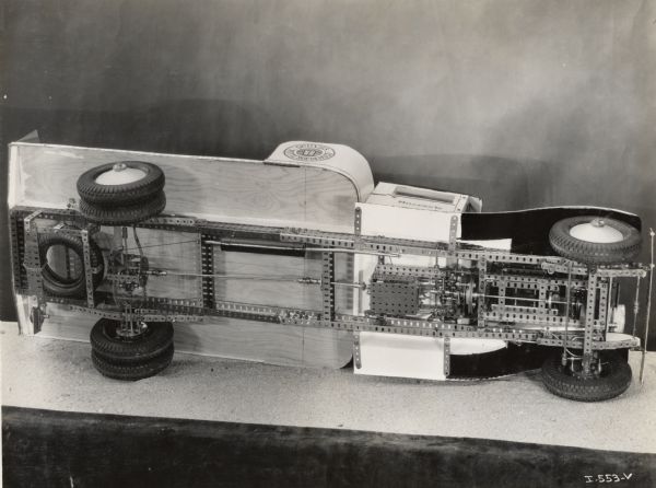 A miniature model of an International truck rests on its side, showing the undercarriage. The model was likely built by Norman Scott of Winnipeg, Manitoba.
