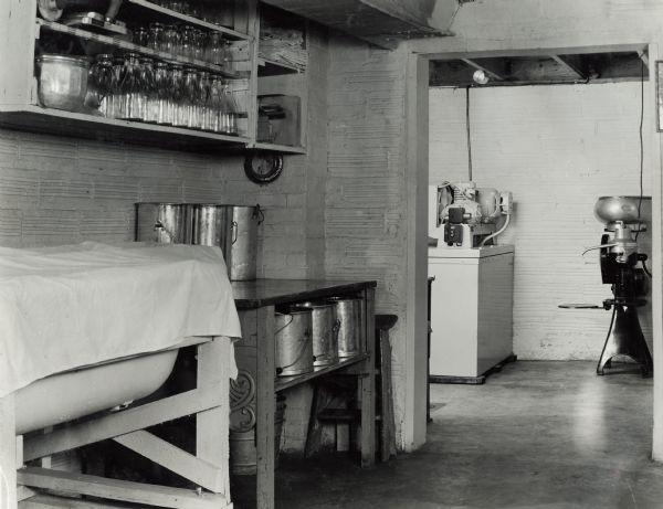 Rooms with bottles, table, canisters and other dairying equipment on the Hazen Pettit farm.  Original caption states: "The vat in the foreground is used for making cottage cheese.  In the next room are shown the McCormick-Deering cream separator and milk cooler which are also used in making buttermilk."
