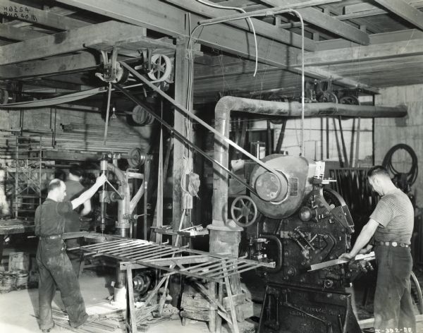 Factory workers at the Ornamental Iron Works. The men are using machinew powered by an International P-12 power unit.