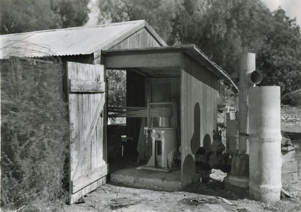 Byron Jackson Deep-well Turbine in a shed. The turbine was powered by an International P-12 power unit. Next to the turbine are water outlets to an irrigation system.