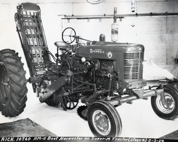 Beet Harvester on Super M Tractor Engineering photograph of a Super M Tractor with beet harvester. The text at the bottom of the photograph reads: "RICH.10760 HM-11 Beet Harvester on Super-M Tractor (Stage 4) 2-3-54."