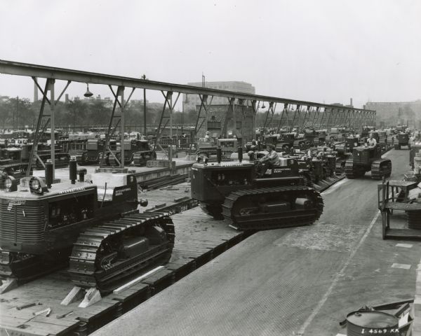 Men loading crawler tractors (TracTracTors), including the TD-18, onto railroad flat cars outside International Harvester's Tractor Works.
