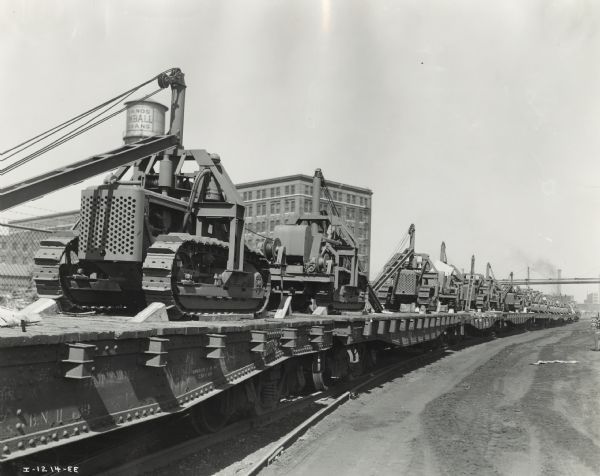 View along railroad track of railroad cars loaded with crawler tractors (TracTracTors) at International Harvester's Tractor Works.