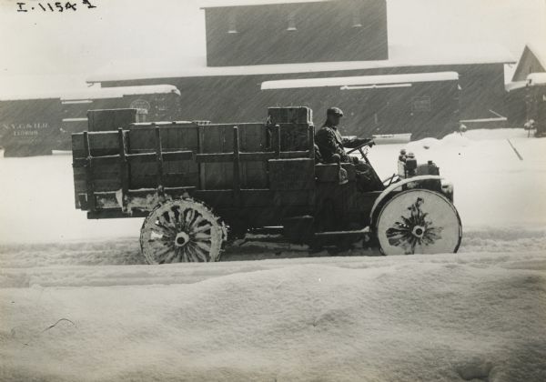 Man driving an International Model E truck in a snow storm. The truck was operated by the National Aluminum Works.