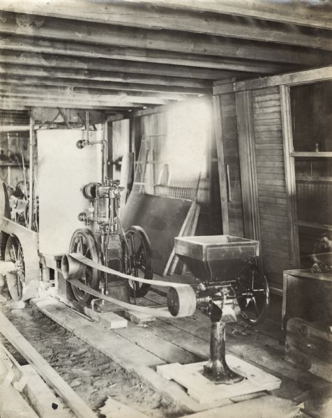 Engine Powered Feed Grinder Stationary engine belted to a feed grinder in a wooden shed.