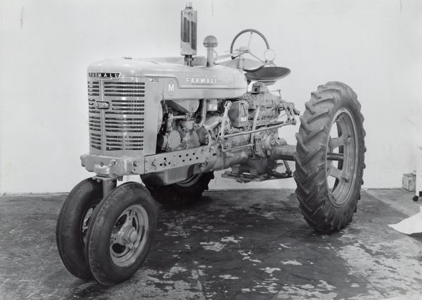 Farmall M Tractor with a Hydraulic Lift Modified Farmall M tractor with a hydraulic lift unit on display in front of a white backdrop. The equipment may be experimental.