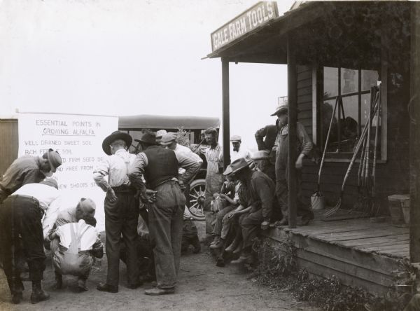 Group of men gathered to test soil for acidity. Original caption reads: "This picture was taken in Dupage County during the Alfalfa Campaign in 1913, showing the speaker testing the soil for acidity. It is necessary to have good sweet soil if your alfalfa is to do well. That is one of the essential points in growing alfalfa."