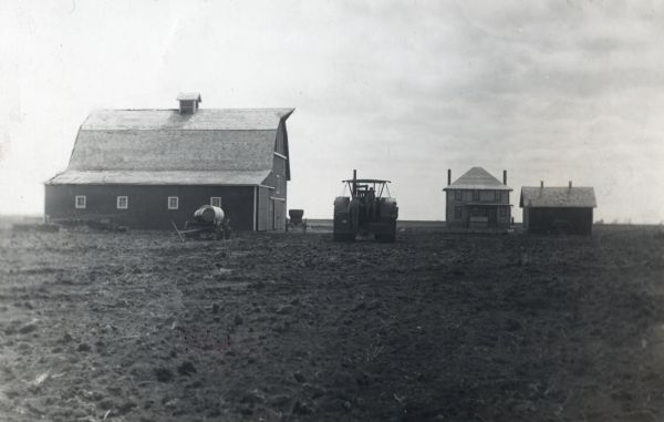 View of a barn, farmhouse, outbuilding and tractor on an International Harvester demonstration farm.