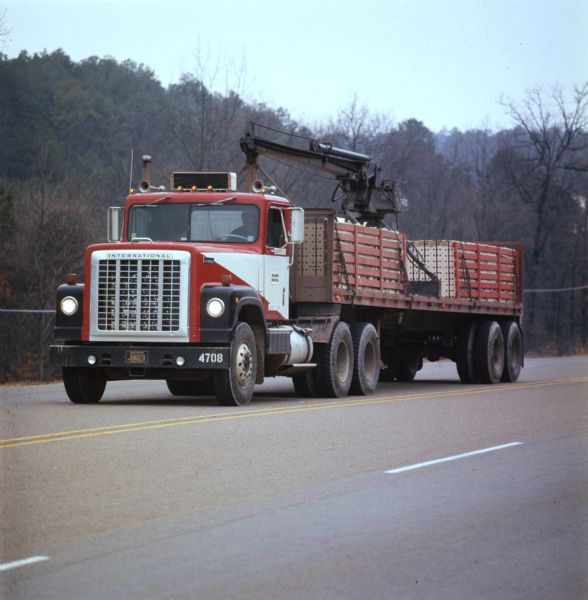 Color photograph of a man driving an International Transtar 4300 truck down a highway with a load for Acme Brick.