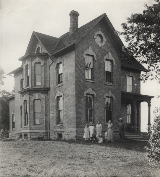Brick Farmhouse Farm family and their dog in front of a two-story brick farmhouse.
