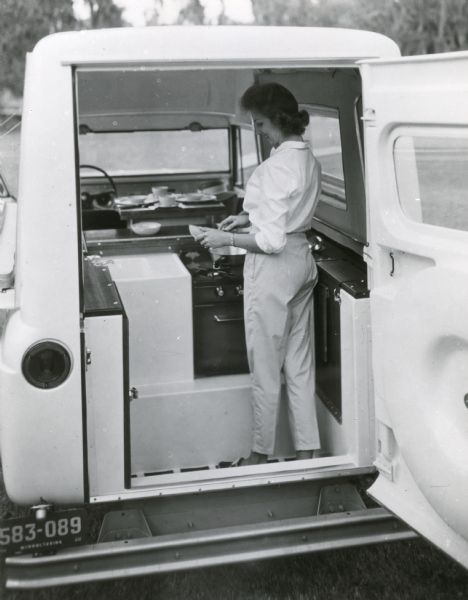 Scout Camper Woman cooking in the back of a Scout set up as a deluxe camper with kitchen.