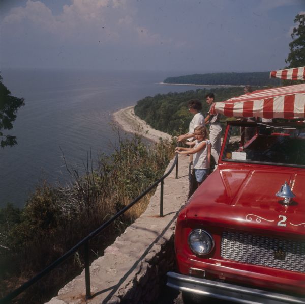 Scout Parked at Overlook of Shoreline Scout parked outdoors at an overlook. A group of people stand at the railing looking down at the water.