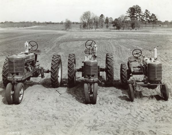 Farmall Tractors Parked in Field Slightly elevated view from front of Farmall tractors parked in a field. From left to right: Farmall M, Farmall H, Farmall A.