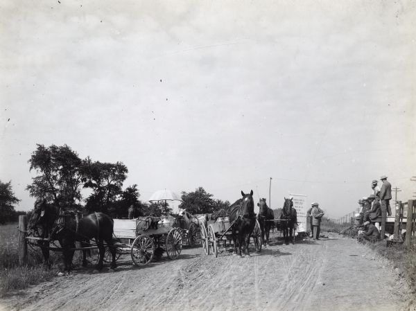 Mr. J.E. Waggoner, International Harvester Company Agricultural Extension Dept. employee, delivering roadside alfalfa lecture to a crowd of farmers arriving at local milk station during Dupage County Alfalfa Campaign of 1913. Pictured in foreground are the farmers' horses and wagons.