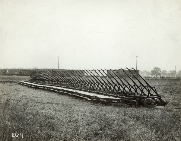 Ten Oliver no. 5 plows attached together for tractor performance testing. In the background a row of railroad cars is passing by.