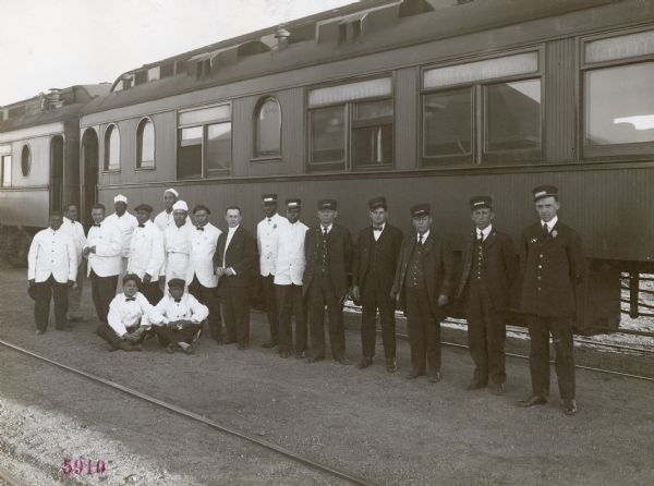 Eighteen man crew for the Union Pacific Silo Special Trip posing for a group portrait in front of railroad cars.