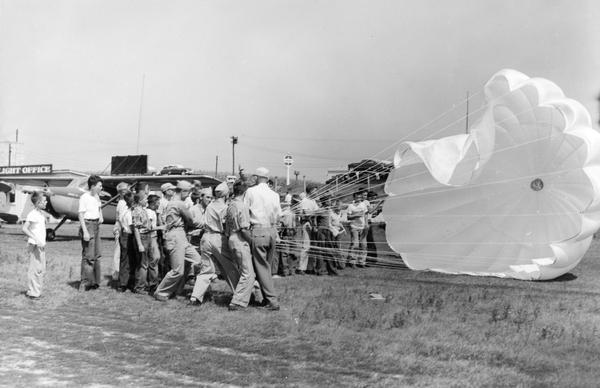 A demonstration of parachute handling for members of a local YMCA by the Waukesha Aviation Club. The club considered such educational activities for young people and the development of enthusiasm for aviation to be its most important goals.