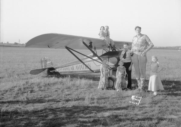 A group of circus performers pose outdoors with a Corben airplane. The tall Man is Jack Earle, and one of the little people is probably Lia Graf.