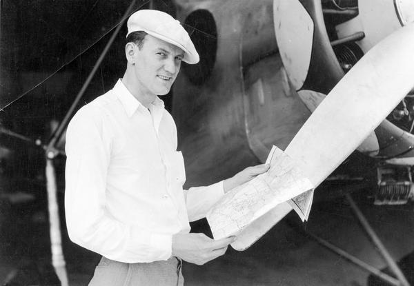 A publicity photograph of Clyde Allen Lee of Larsen, Wisconsin, standing beside the Stinson airplane he rebuilt to attempt a trans-Atlantic crossing to Oslo, Norway. Lee's airplane disappeared over the North Atlantic in 1932.