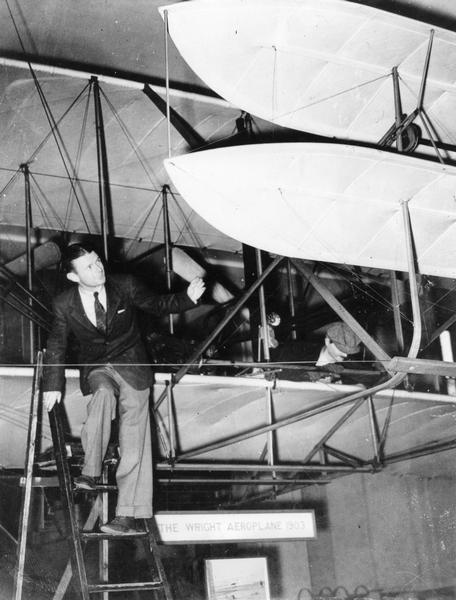 After his "mistaken" trans-Atlantic flight to Great Britain, Douglas "Wrong Way" Corrigan visited the original 1903 Wright Flyer then on display at the Science Museum in London. Although aviation publicist Harry Bruno did not represent Douglas Corrigan, he used this photograph on behalf of an organization that he did represent, the Association of Men with Wings.  The AMW was formed to bring the Flyer back to the United States. Many may be surprised to know that the 1903 Flyer has been on display at the Smithsonian only since 1948.  This happened because the Smithsonian had angered Orville Wright by attributing the first heavier-than-air flight to the Langley Aerodrome, not the Wright Flyer. As a result, Orville Wright shipped the Flyer to Great Britain in 1926. Eventually the Smithsonian apologized, and shortly before his death, Wright relented. The Wright Flyer was put on exhibit at the Smithsonian in 1948.