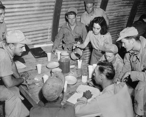 Betty Sullivan, a Red Cross worker, serves coffee in the interrogation room at Kobler Field, Saipan, for a B-29 flight crew that had just returned from a bombing mission.  This photograph is one of a large of number of studies taken by Milwaukee photographer Dickey Chapelle during the latter stages of the war in the Pacific.