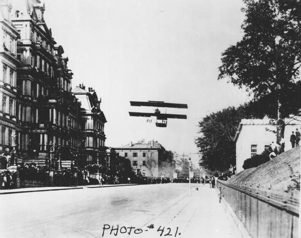 Claude Graham-White, winner of the Gordon Bennett Race and several other important races in 1910, flying a Farman plane over Washington, D.C. Graham-White had just landed on a street by the White House.