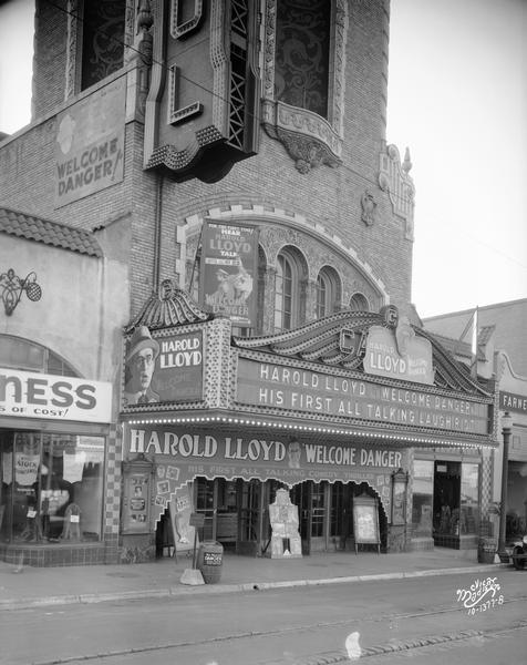 View from street of the facade of the Capitol Theatre with marquee advertising "Harold Lloyd," "Welcome Danger," and  "His first all talking comedy thriller." The theater is located at 209 State Street.