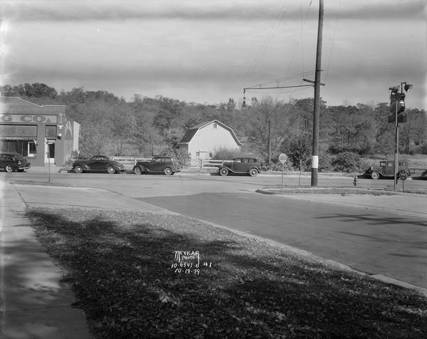 Intersection of Grand and University Avenues, looking north from Grand Avenue, with a barn, Madison Nehi Company (Royal Crown Cola), 2600 University Avenue, and some automobiles.