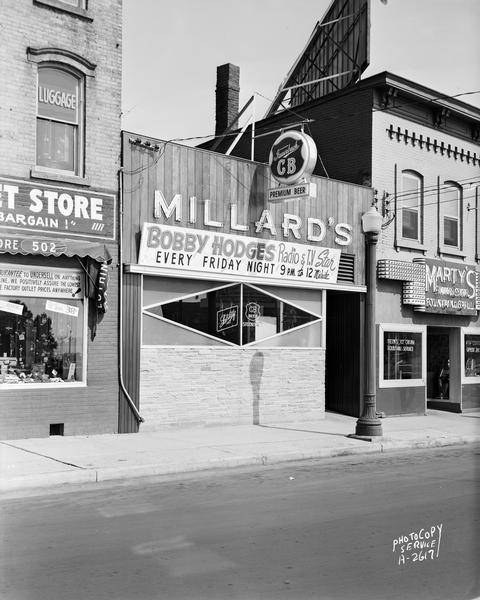 Millard's Tavern, 504 East Wilson Street with Fauerbach CB beer sign and "Bobby Hodges radio & TV star, Every Friday Night." Also shows Marty's Sandwich Shop, 506 East Wilson Street and Factory Outlet Store, 502 East Wilson Street.