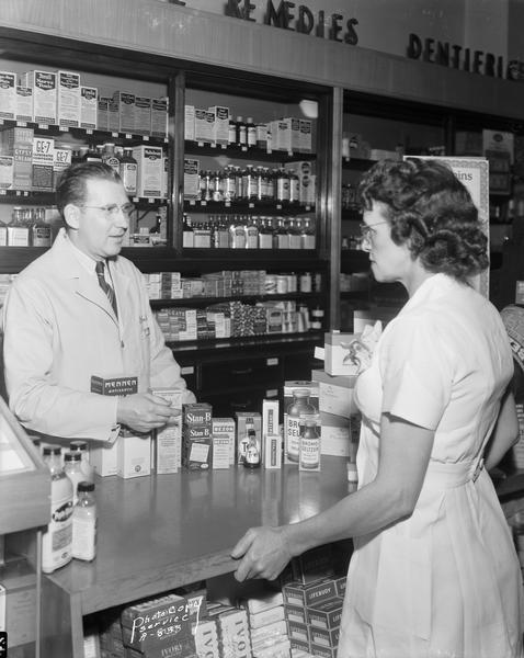 Rennebohm drugstore pharmacist showing over-the-counter medical products to a customer.