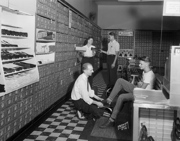 Clerks help customers try on shoes at the Thom McAn Shoe Store, 224 State Street.