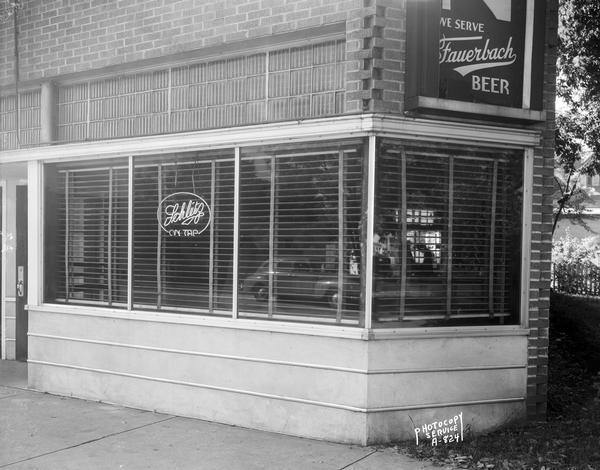 Arian's Tavern, 2517 University Avenue. The windows have Venetian blinds, and a Schlitz beer neon sign. At the corner of the building on the right is a "We Serve Fauerbach Beer" sign.