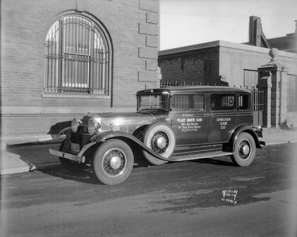 Checker Cab Company flatrate cab in front of the Chicago & Northwestern railroad depot at 148 S.Blair Street.