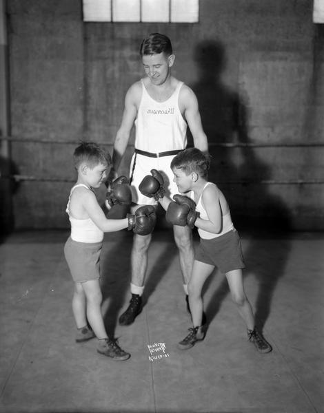 Young boys, Alex and Bobby McCormick, posing as boxers in front of John Walsh, University of Wisconsin boxing coach.