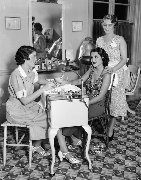 Actress Raquel Torres gets a facial from Ida Osthoff, manager of Grace Beauty Shop 132 State Street, while Josephine Armbrecht, beauty operator, gives her a manicure.