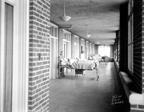 View towards patients in beds, with nurses, on the sun porch at the Lake View Tuberculosis Sanitarium.