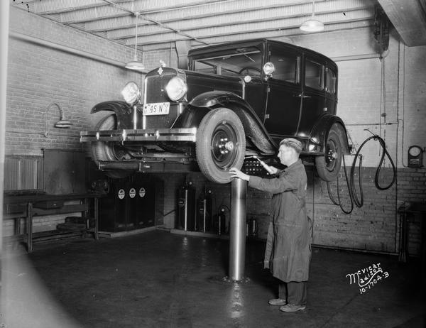 Mechanic Greasing Wheel Bearings A mechanic employed by Capital Garage, 608-612 East Washington Avenue in Madison, greases the wheel bearings of an automobile on the hoist.
